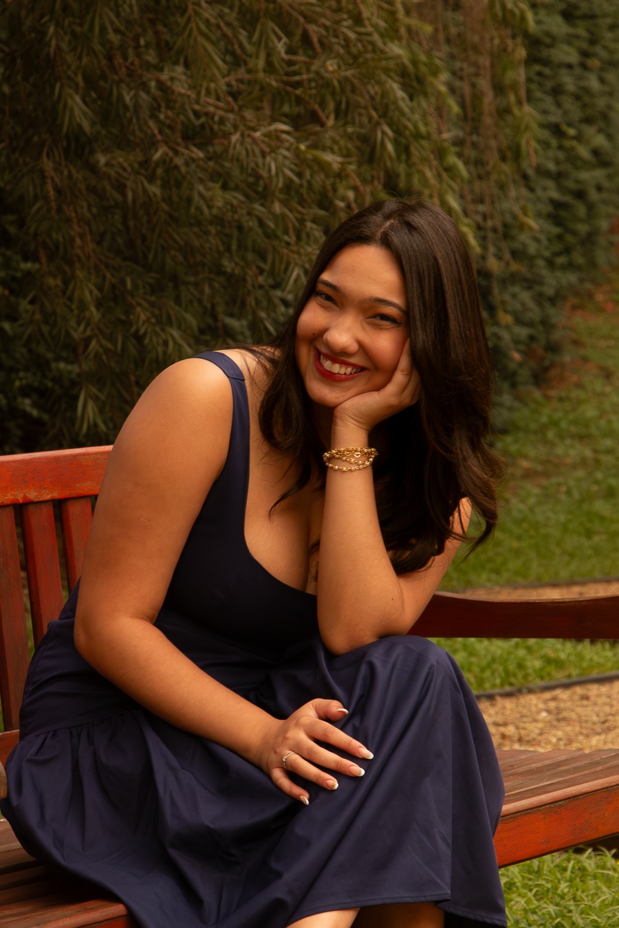 Teacher Gabi, fundadora da Fluency Garden English School, sentada em um banco em um jardim